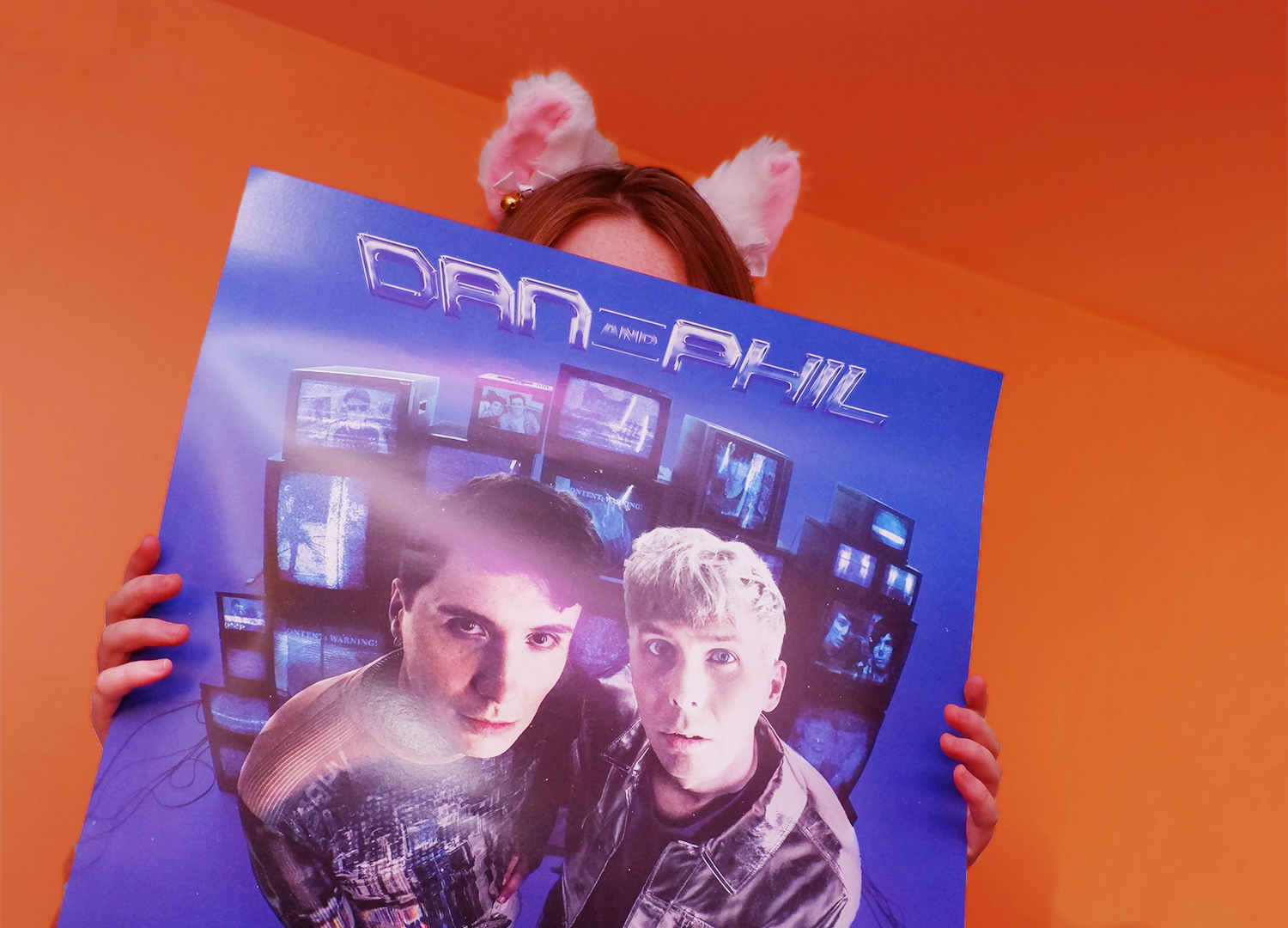 A person holding a promotional poster of the Dan and Phil concert